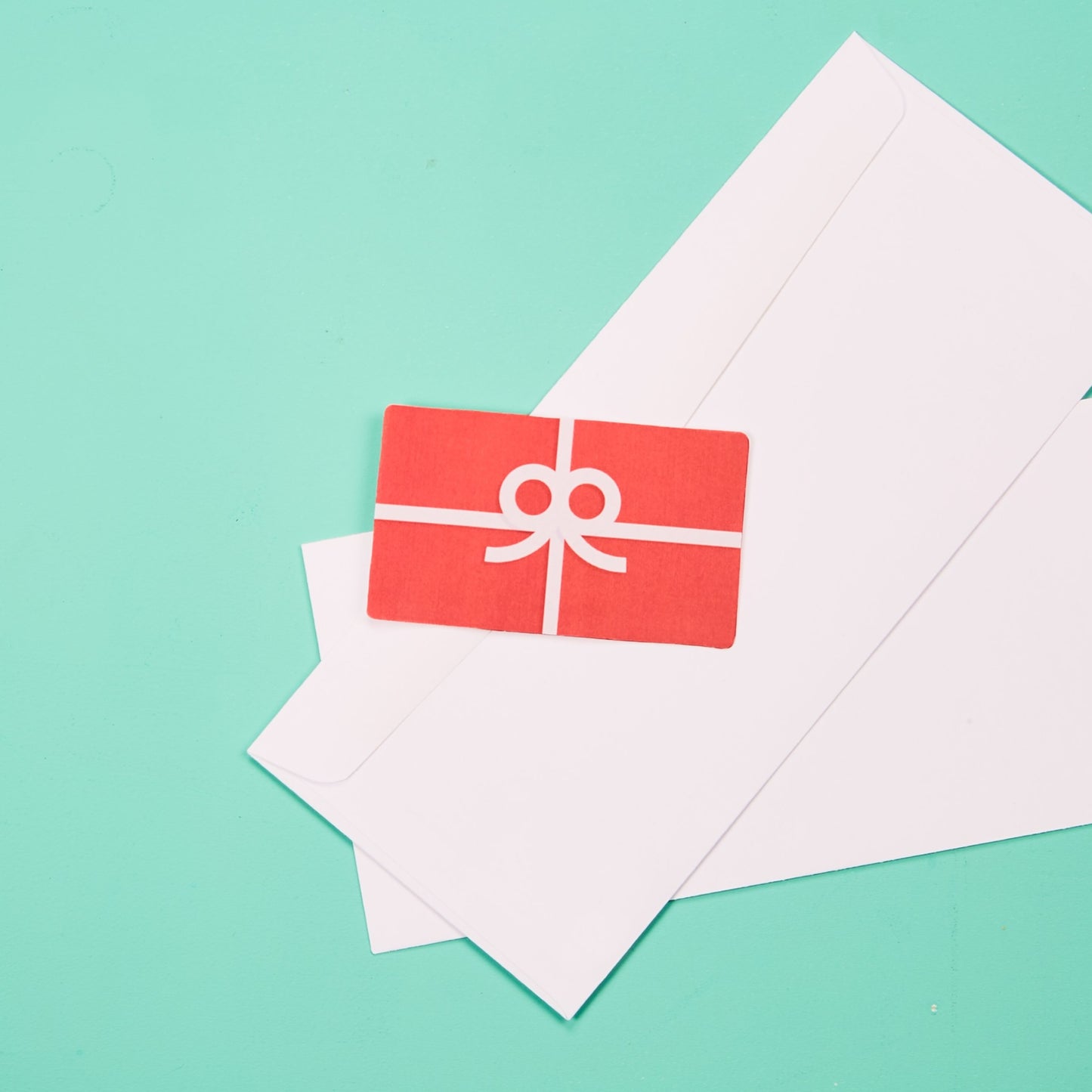 red gift card placed on top of 2 white envelopes